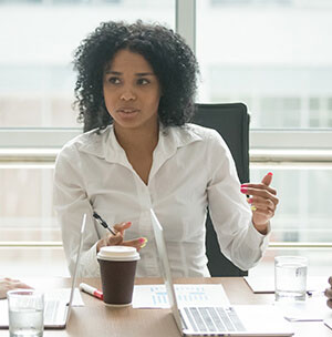 person-leading-meeting A project management consultant sitting at desk with coffee offering guidance.